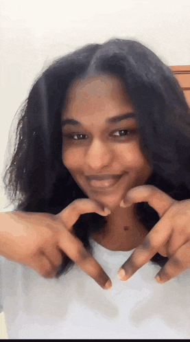 a woman makes a heart shape with her hands