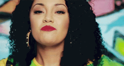 a woman with curly hair and red lipstick is making a face .