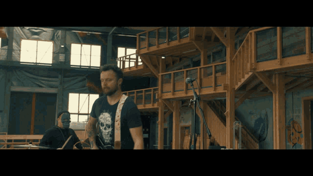 a man with a skull on his shirt is playing a guitar