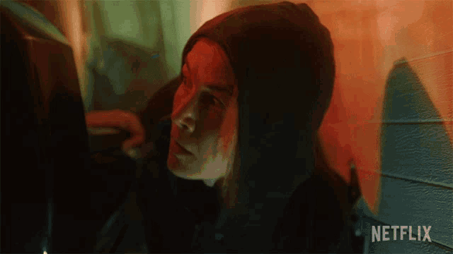 a woman in a hooded jacket is looking at a computer screen with netflix written on the bottom