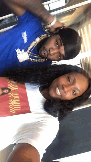 a man and a woman are posing for a picture and the man is wearing a blue shirt that says ' nike '