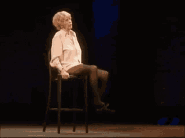 a woman is sitting on a stool on a stage