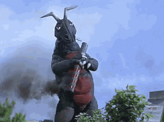 a monster with horns is holding a cannon in his hand .