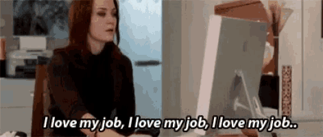 a woman is sitting at a desk with a computer and saying `` i love my job , i love my job . ''