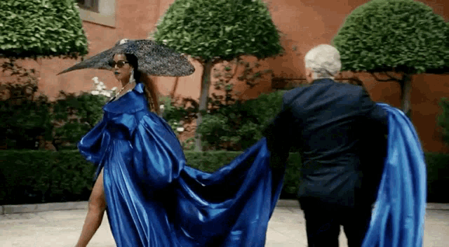 a woman in a blue dress and a man in a suit are standing next to each other