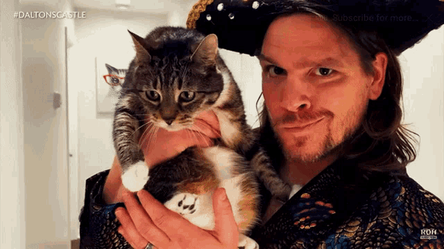 a man in a pirate hat holds a cat