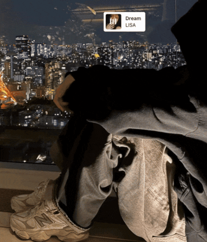 a person sitting in front of a window with a dream lisa sticker