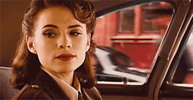 a woman in a uniform is sitting in a car looking out the window .