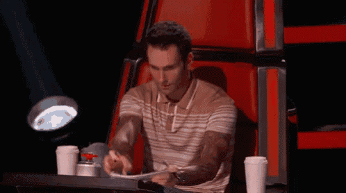 a man is sitting in a red chair with two cups of coffee
