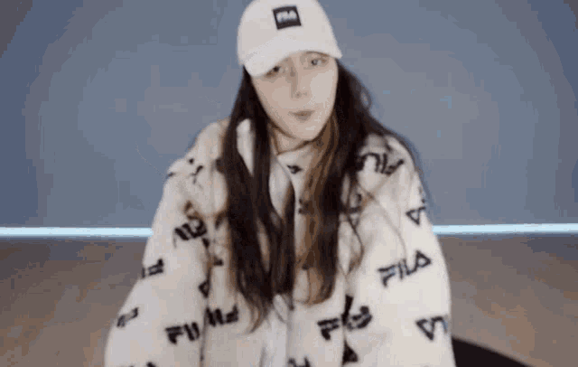 a woman wearing a white hat and a white jacket with fila written on it
