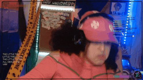 a woman wearing a pink hat and headphones is standing in front of a halloween sign
