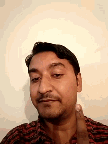 a man with a beard and a red and black plaid shirt looks down at the camera