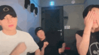 a group of young men are standing in a room covering their faces .