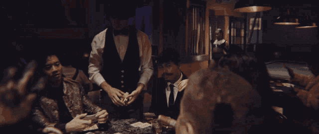 a group of men are sitting around a table with cards on it