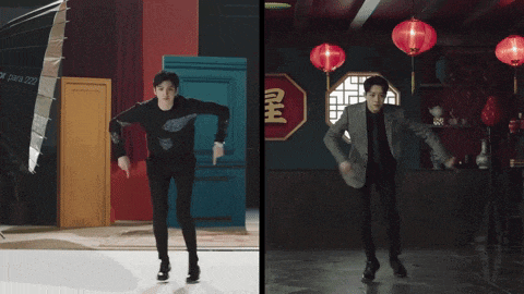 a man in a suit and a man in a black shirt are standing next to each other in a room with red lanterns