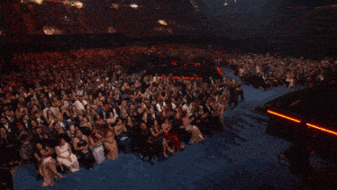 a crowd of people sitting in a dark room with a red light in the middle
