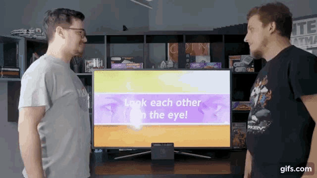 two men are standing in front of a television screen that says look each other in the eye