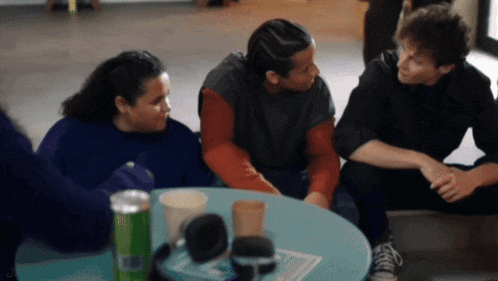a group of people sit around a table with a can of monster energy drink on it