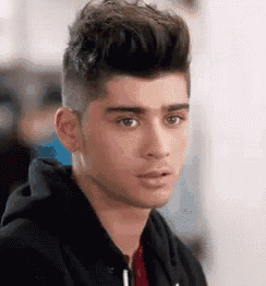 a close up of a young man wearing a black hoodie .