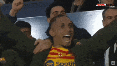 a soccer player wearing a spotify shirt celebrates with his teammates