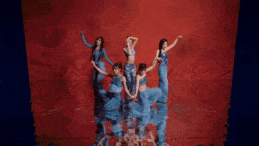 a group of women in blue feathered outfits are dancing on a red background