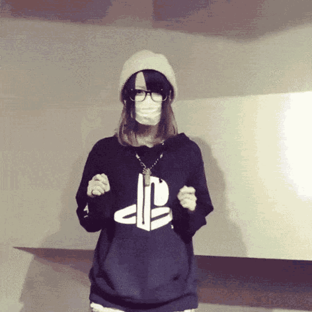 a woman wearing a mask and a black hoodie with the playstation logo on it