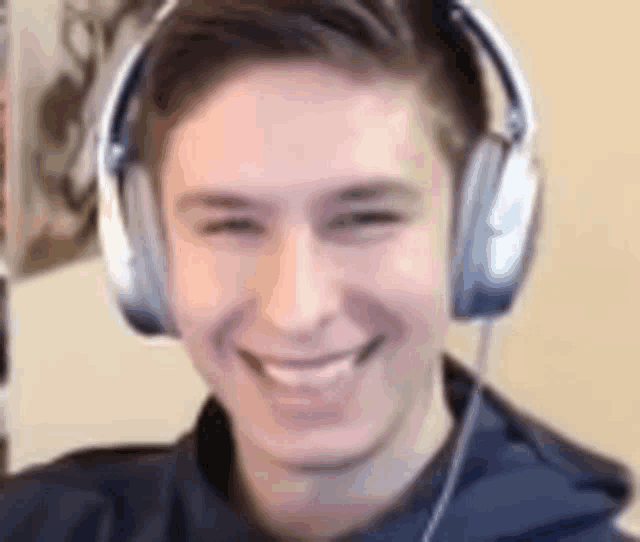 a young man wearing headphones is smiling while looking at the camera .