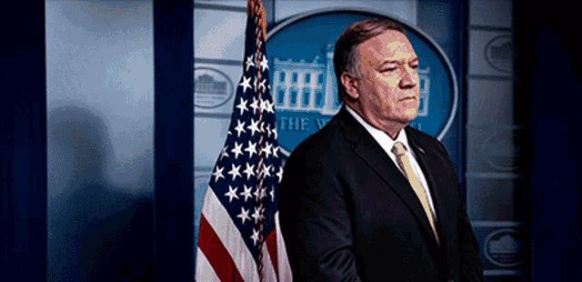 a man in a suit and tie stands in front of the white house