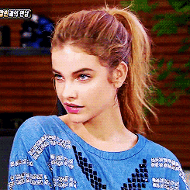 a woman with a ponytail is wearing a blue sweater with chinese writing