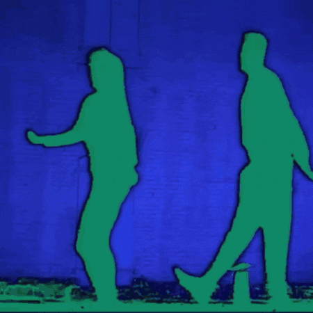 two silhouettes of a man and a woman walking in front of a blue wall