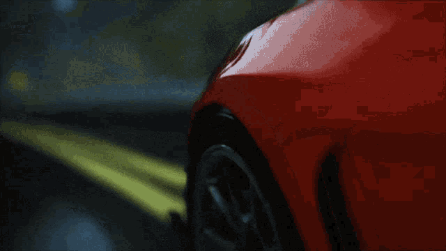a close up of a red car 's wheel in the rain