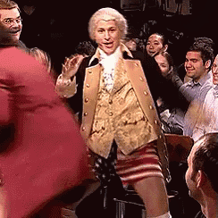 a man in a suit is dancing in front of a crowd .