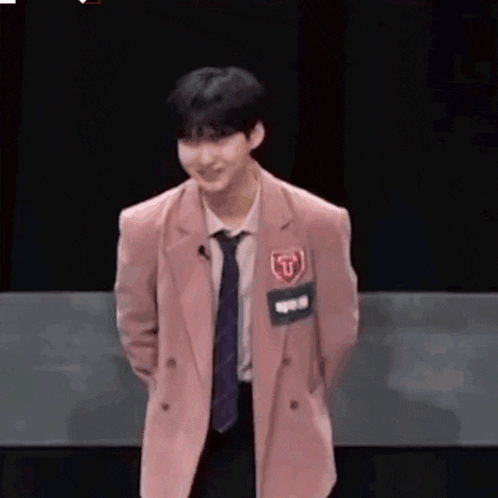 a young man is wearing a pink jacket and tie .
