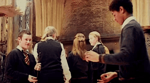a group of people are standing in a room holding wands and talking to each other .
