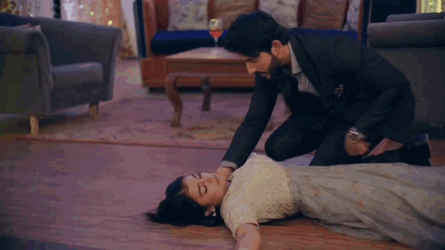 a man is kneeling next to a woman laying on the floor .