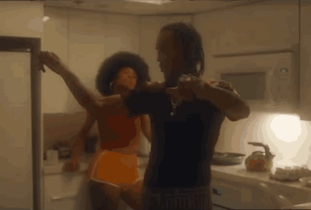 a man and a woman are dancing in a kitchen