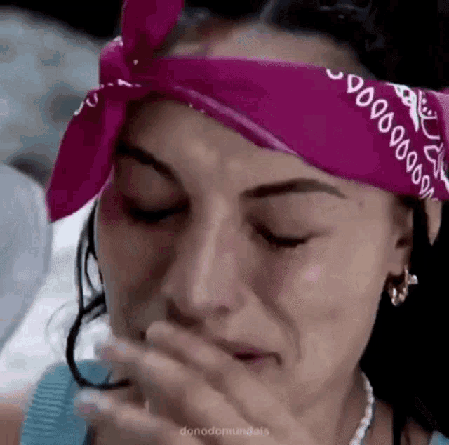 a woman wearing a pink bandana on her head is crying .