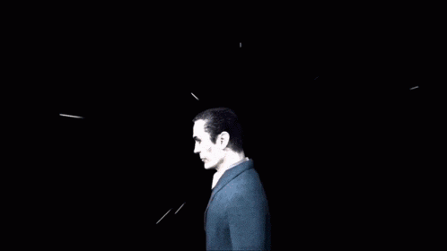 a man in a suit is standing in the dark looking up at the sky .