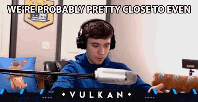 a man wearing headphones is sitting in front of a microphone and talking into it .