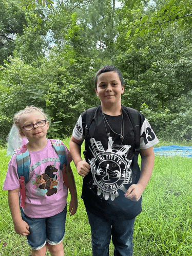 a boy wearing a shirt that says the city of new york stands next to a girl