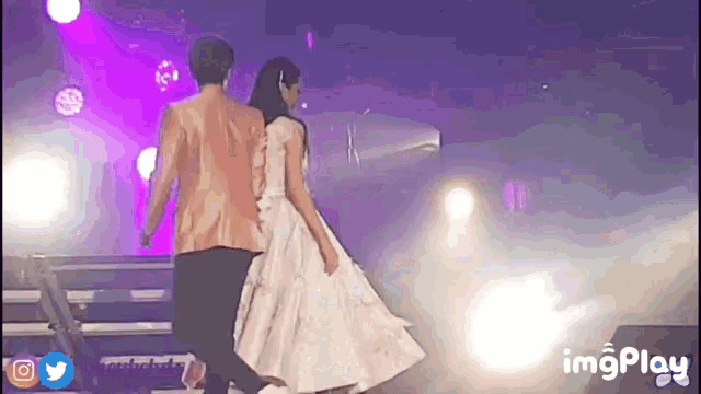 a man and a woman are walking on a stage .