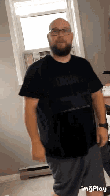 a bald man with a beard wears a black tommy hilfiger shirt