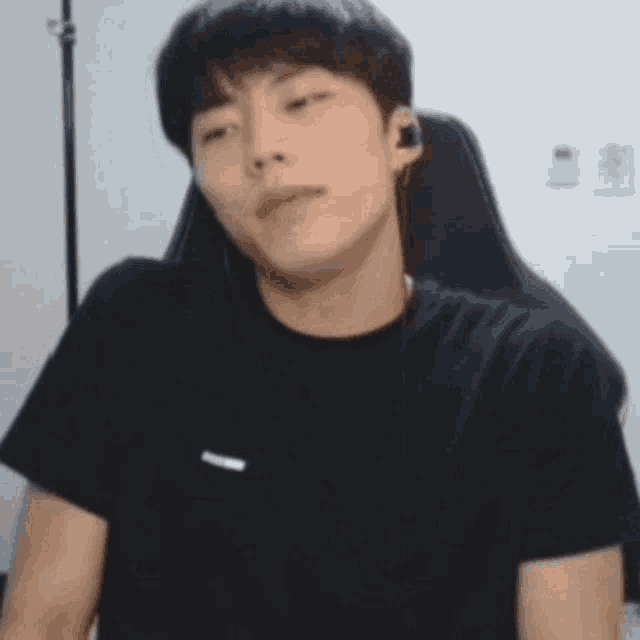 a young man wearing headphones is sitting in a chair and making a funny face .