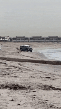 a car is upside down on the beach