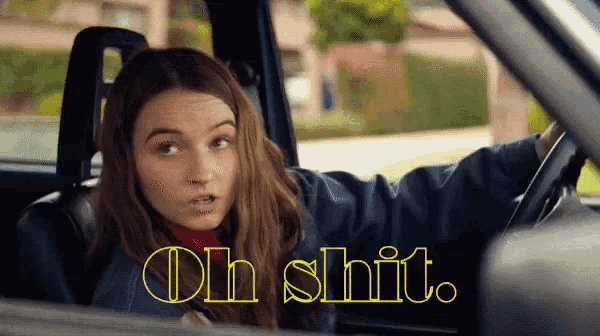 a woman sitting in a car with the words oh shit written in yellow