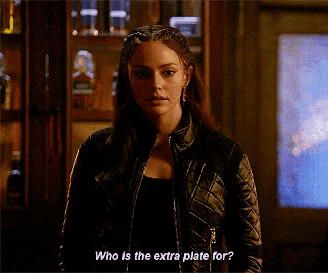 a woman in a black leather jacket is asking who is the extra plate for