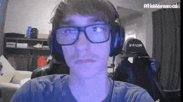 a man wearing glasses and headphones has the word s-racer on the back of his chair