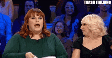 two women are sitting in front of a crowd with the words trash italiano written on the bottom .