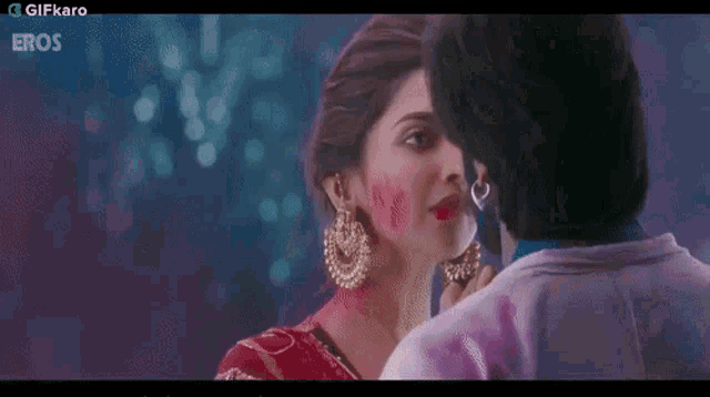 a man with holi paint on his face is kissing a woman .