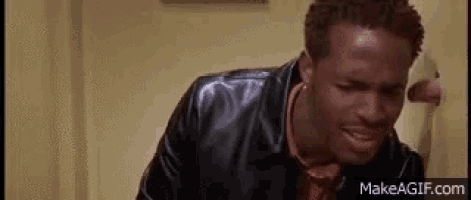 a man in a black leather jacket is standing in a bathroom .